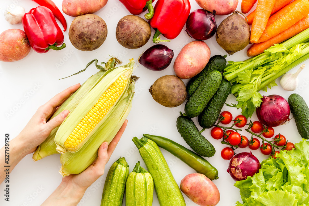 Pick vegetables. Corn in hands near autumn harvest on white background top-down