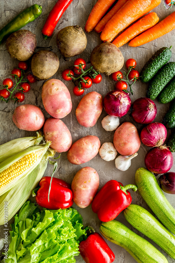 Fresh vegetables still life. Potato, cucumber, beet carrot, greenery on stone background top-down