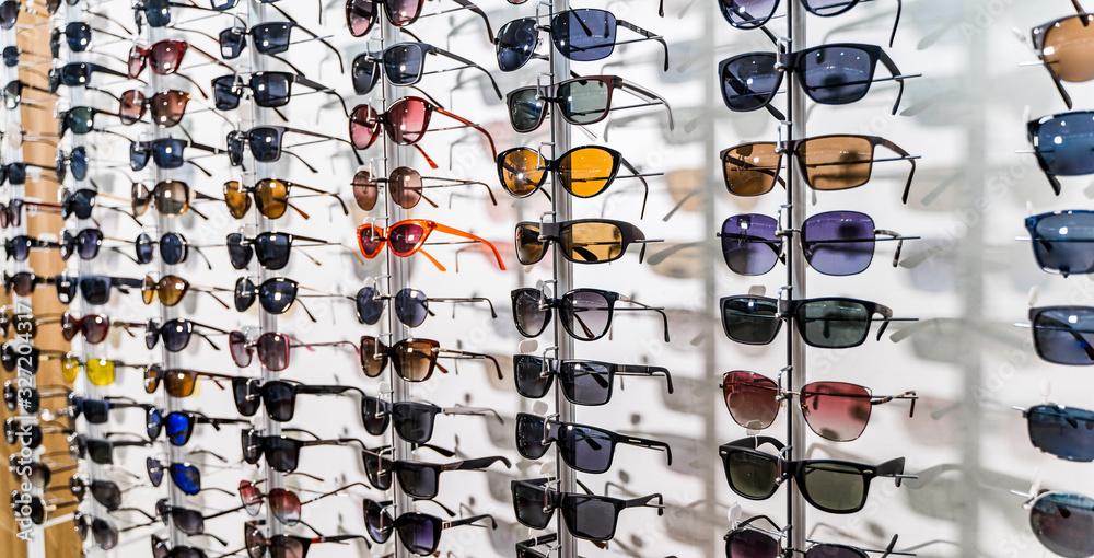 Sunglasses in the shop display shelves. Stand with glasses in the store of optics.