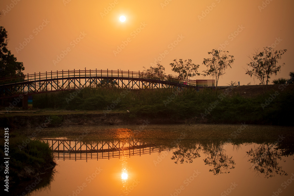 The reflection of the old bridge on the river,The silhouette of the old wooden bridge at sunrise or 