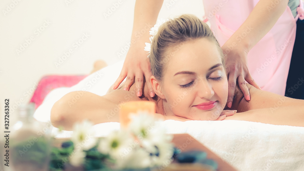 Relaxed woman getting back massage in luxury spa with professional massage therapist. Wellness, heal