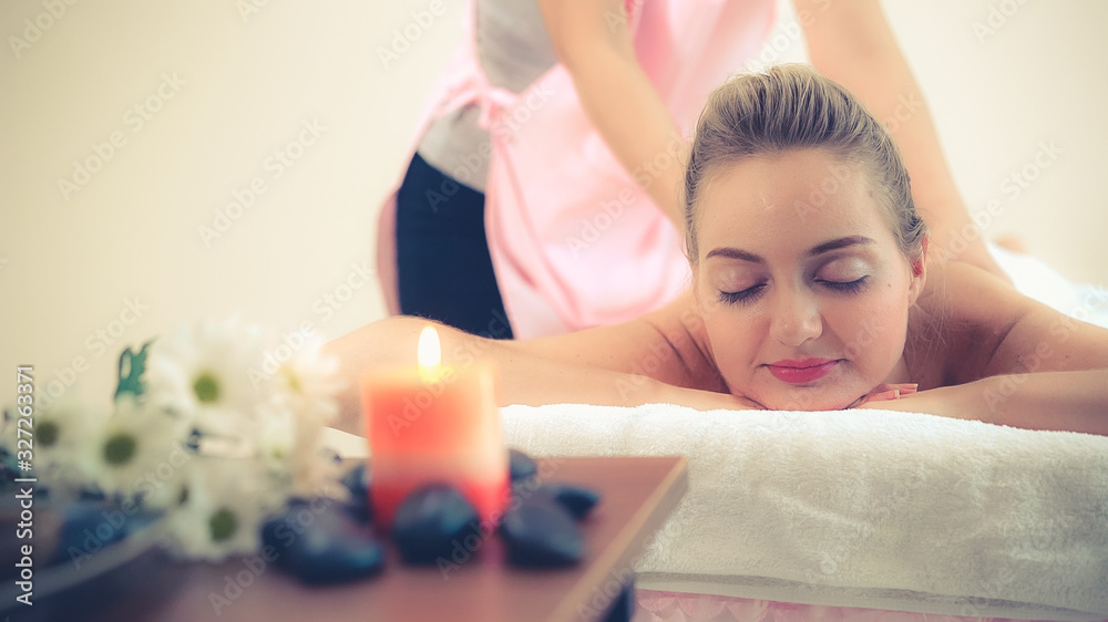 Relaxed woman getting back massage in luxury spa with professional massage therapist. Wellness, heal