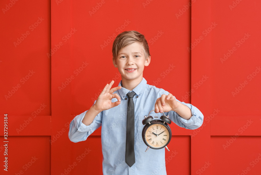 Little boy with alarm clock showing OK on color background