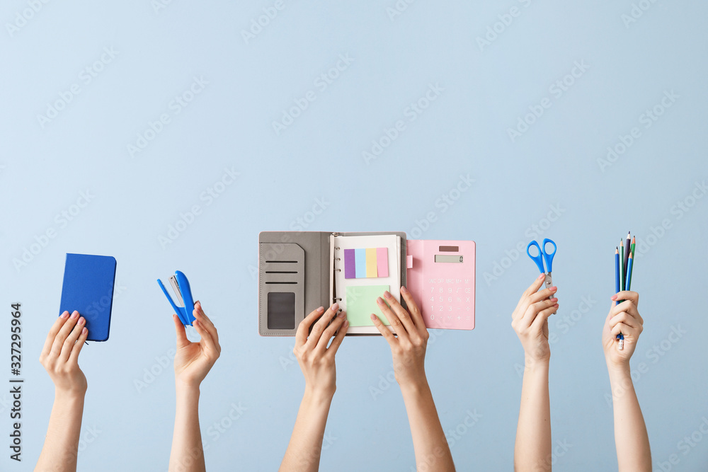 Many hands with school supplies on color background