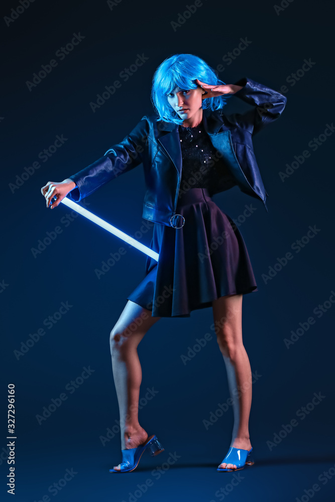 Toned portrait of beautiful woman with neon lamp on dark background