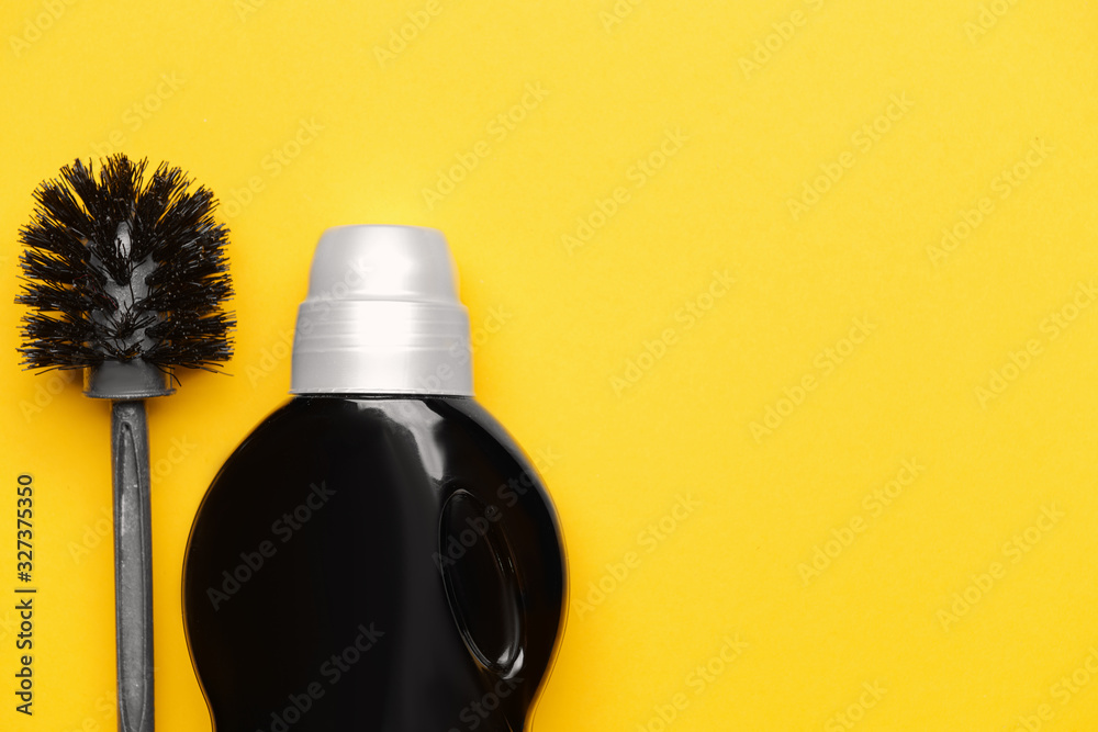 Bottle of detergent with brush on color background