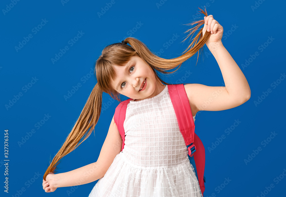 Cute little schoolgirl on color background