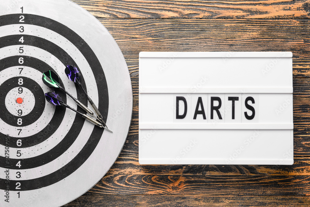 Dartboard with darts on wooden background