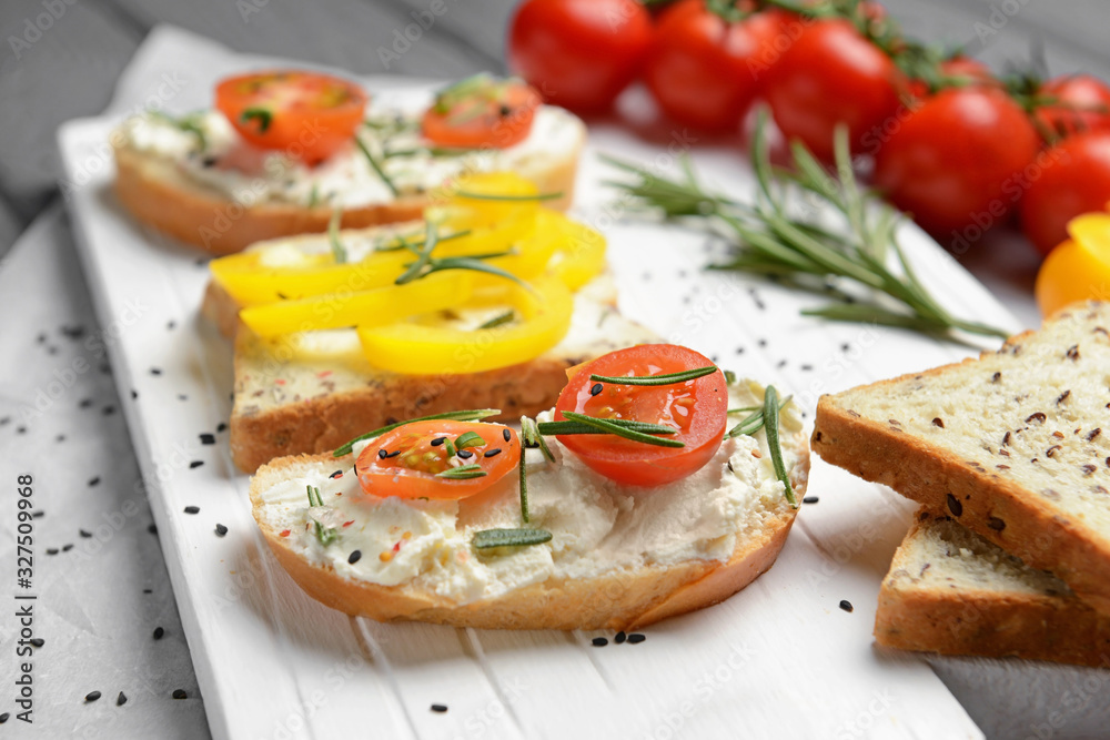 Sandwiches with tasty cream cheese and vegetables on board