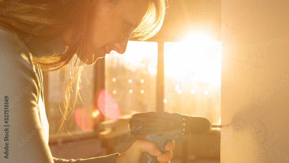 LENS FLARE: Woman is doing a mans job by unscrewing bolts out of a plaster wall