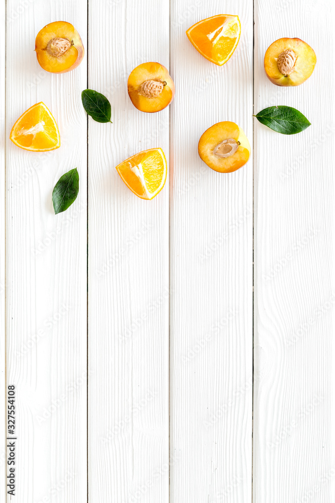 Peach slices and leaves pattern on white wooden background top-down copy space frame