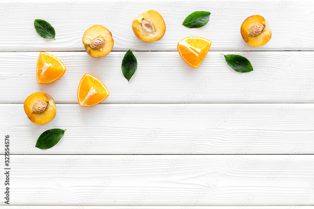 Peach slices and leaves pattern on white wooden background top-down copy space frame