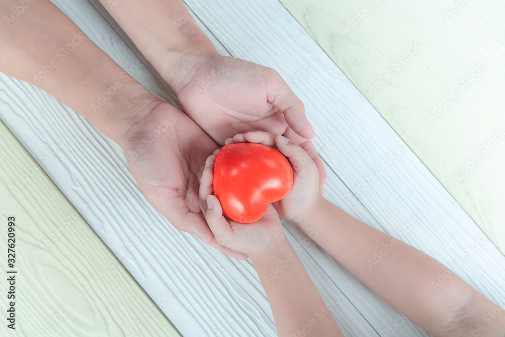 Red heart in hands of Father and son. Love and health care.