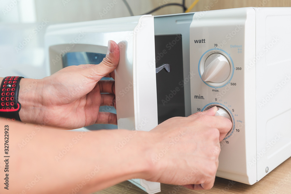 Womans Hands Closing Microwave Oven Door And Preparing Food in microwave.