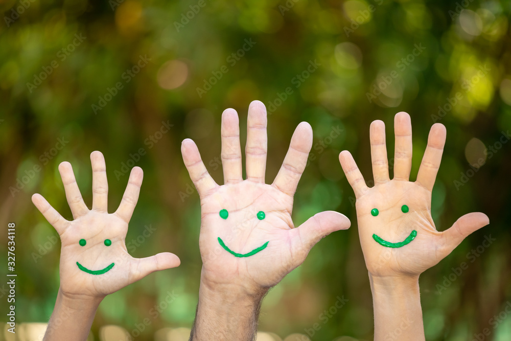 Painted smiley face on the palms against green background