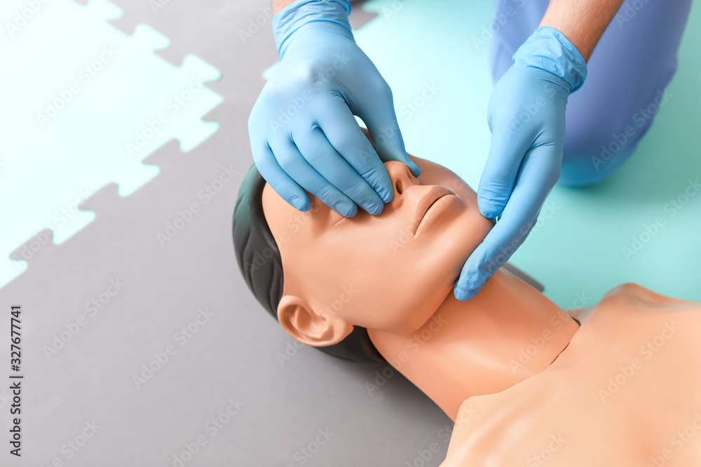 Instructor demonstrating CPR on mannequin at first aid training course