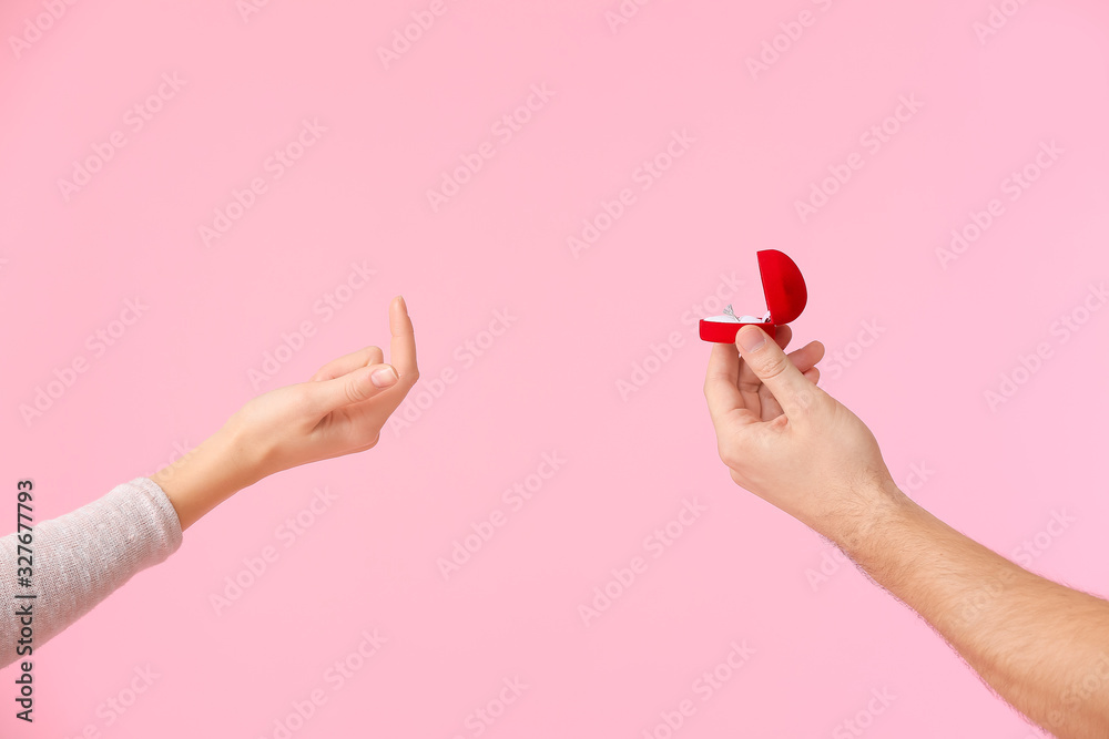 Hand of young man proposing to his girlfriend on color background