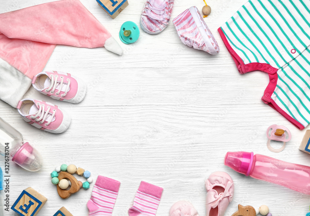 Frame made of baby clothes and accessories on white wooden background