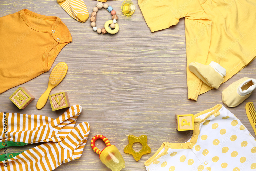 Frame made of baby clothes and accessories on wooden background