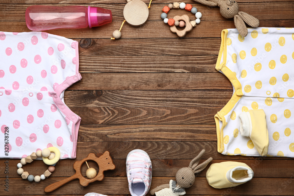 Frame made of baby clothes and accessories on wooden background