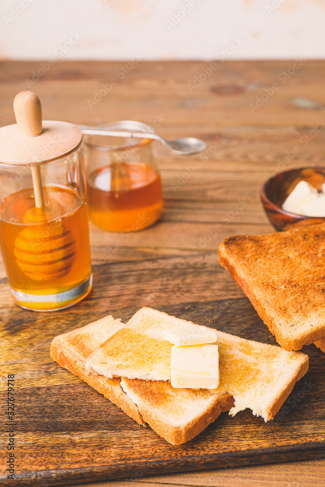 Tasty toasted bread with honey and butter on table