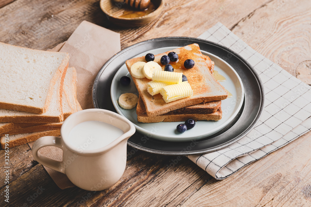 Tasty toasted bread with honey, butter and fruits on plate