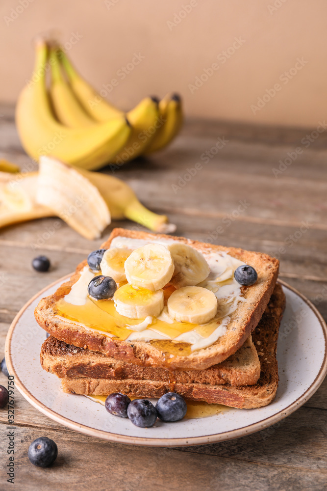 Tasty toasted bread with honey, butter and fruits on plate