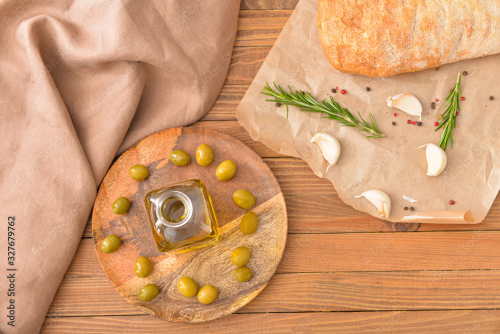 Bottle of tasty olive oil with bread and spices on wooden table