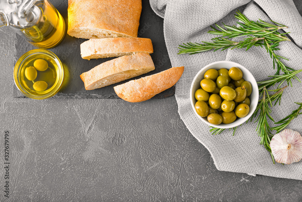 Tasty olive oil with bread on dark background