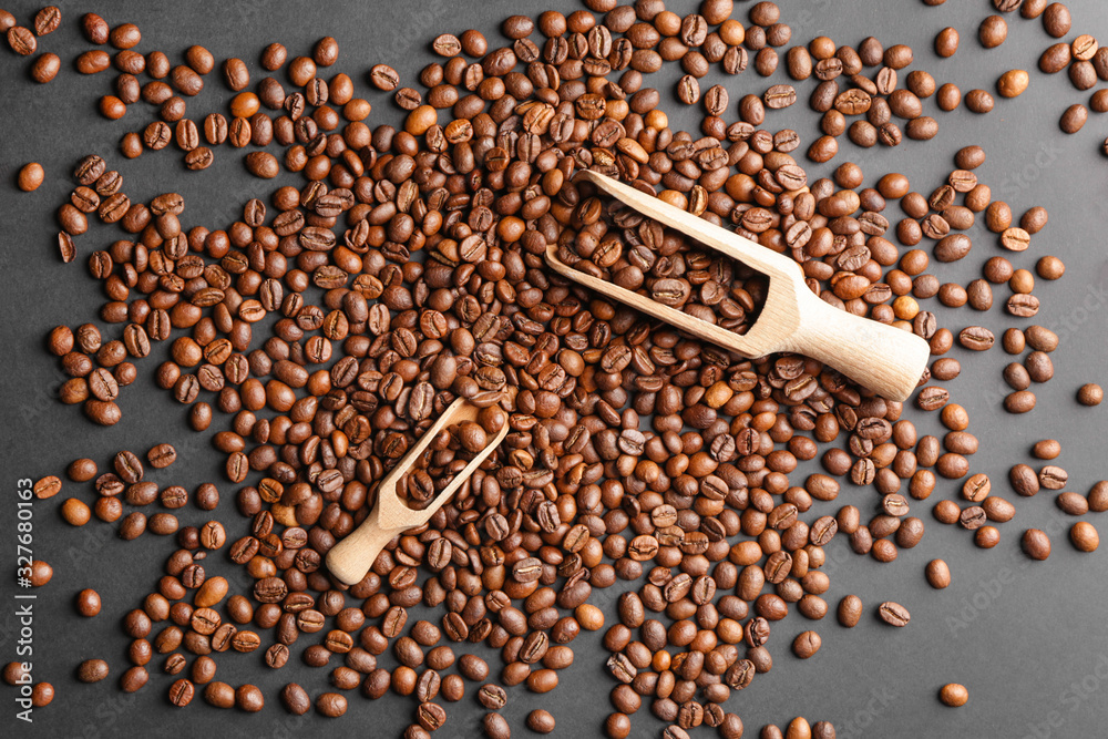 Many coffee beans and scoops on dark background