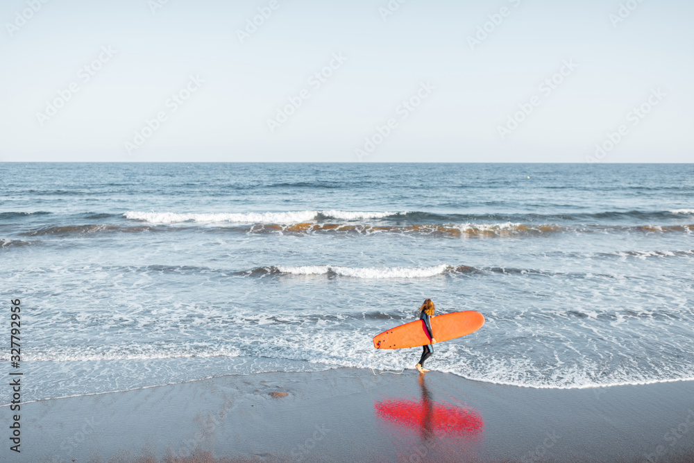 美丽的日落海景，日落时冲浪者拿着红色冲浪板行走