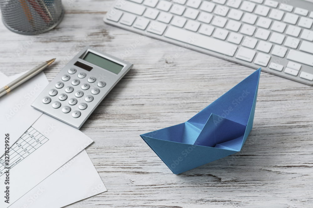 Office workspace with blue paper ship