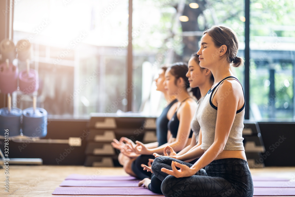 Group of Multi ethics people learning Yoga class in fitness club. Female Caucasian instructor leadin