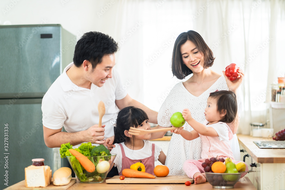 Lovely cute Asian family making food in kitchen at home. Portrait of smiling mother, dad and childre