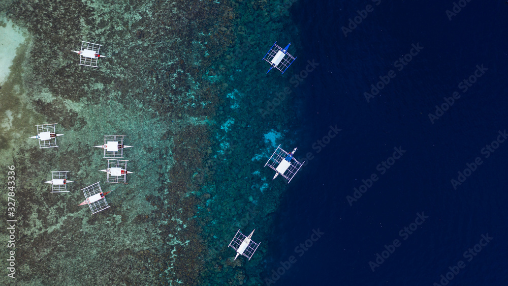 Aerial top down view of boat moving in open sea with clear and turquoise water on over coral reef,  