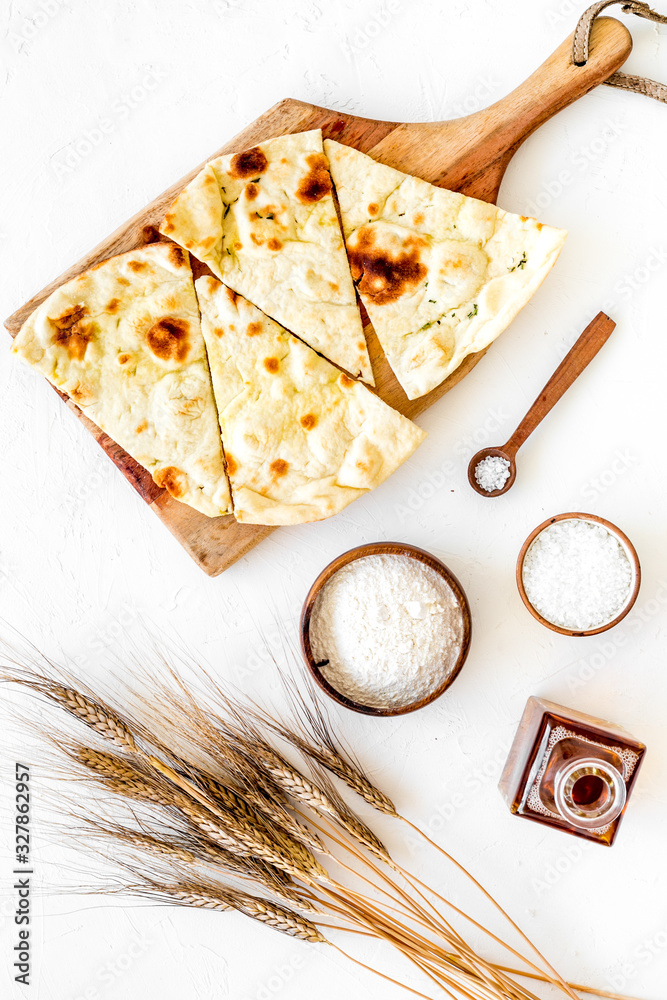 Focaccia ingredients. Wheat ears, flour, oil near bread on white background top-down