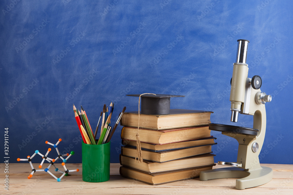 Education and sciences concept - books on the teacher desk in the auditorium, chalkboard on the back