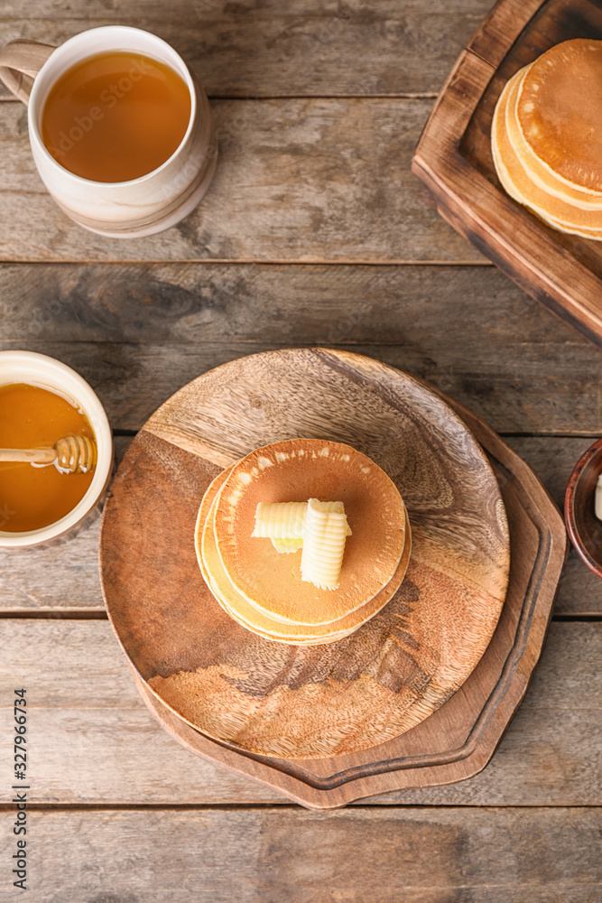 Tasty pancakes with honey and butter on table