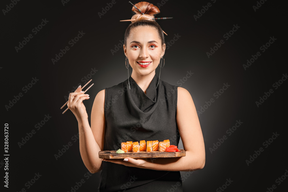 Beautiful woman with tasty sushi on dark background