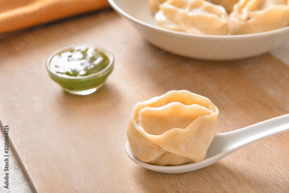 Spoon with oriental dumpling and on table