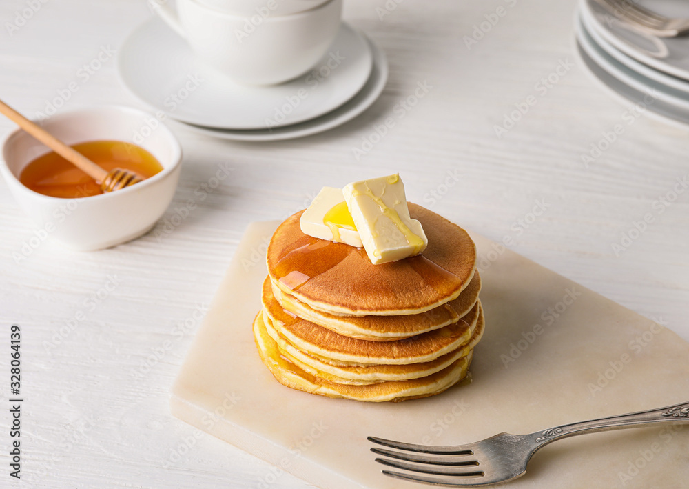 Tasty pancakes with honey and butter on table