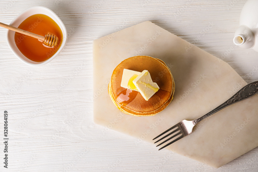 Tasty pancakes with honey and butter on table