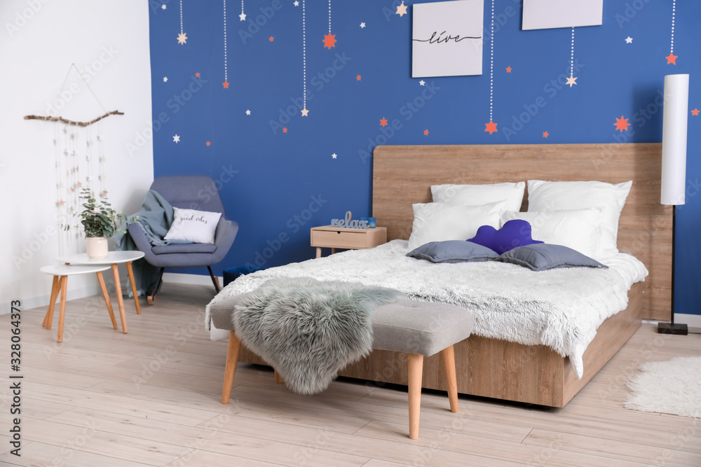 Stylish interior of room with big bed near blue wall