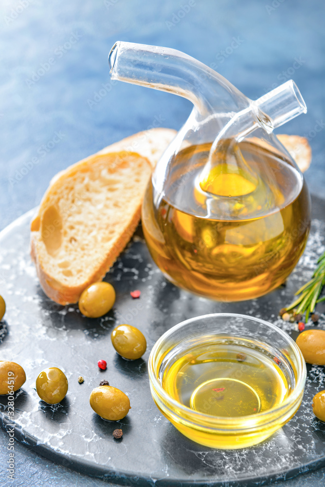 Tasty olive oil with bread on dark background