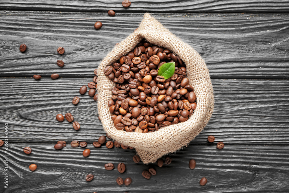 Bag with coffee beans on wooden background