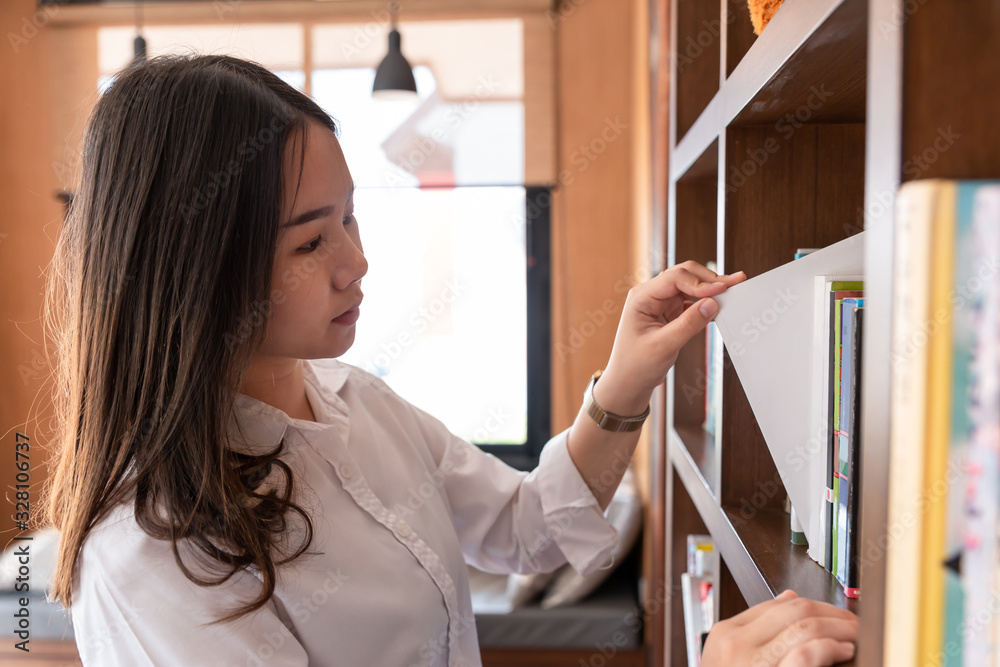 Asian Girl find the book on bookshelf in library