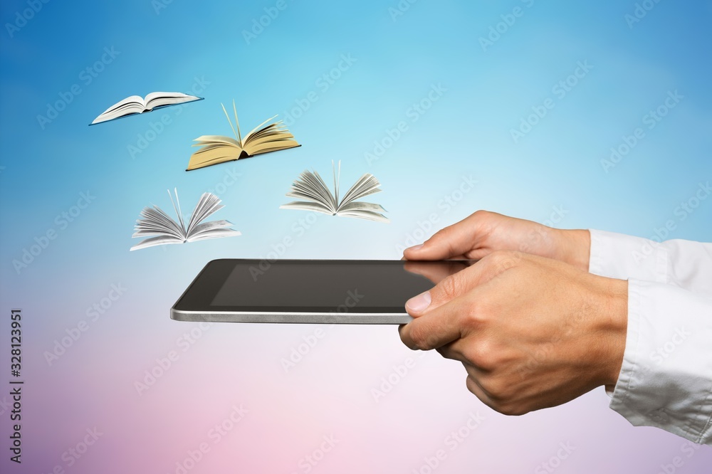 Male hands holding digital tablet near little flying books