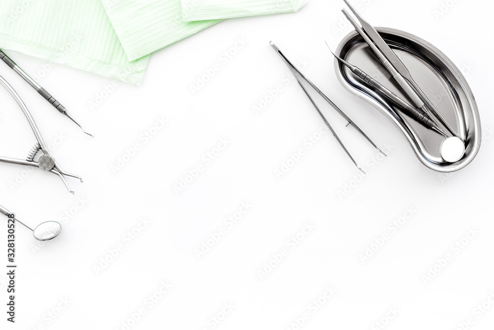 Stomatological tools in tray on dentists desk on white background top-down frame space for text