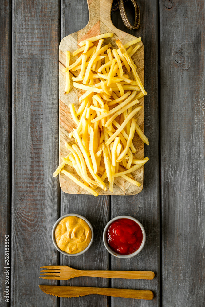 French fries served on cutting board on wooden table top-down