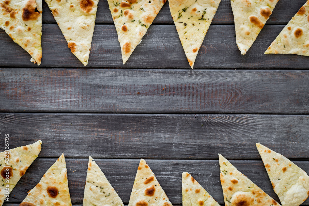 Focaccia pieces frame on dark wooden background top-down copy space